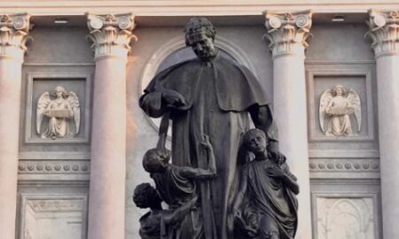 Estatua En Honor A Don Bosco Donde El Santo Juega Con Unos Niños
