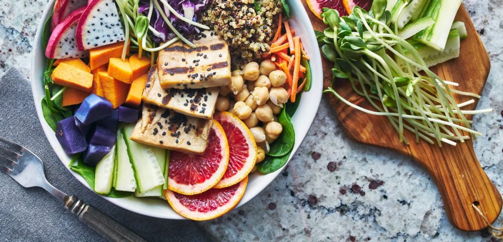 Mangiare vegano. Un piatto ripieno di frutta, tofu e altri alimenti vegani.