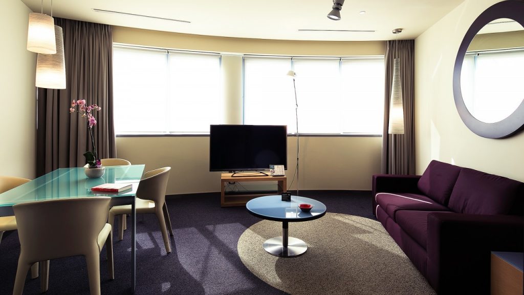 Nella foto si vede l'interno della stanza del THotel Executive Suite. Si vedono le finestre, il divano e il tavolo.
