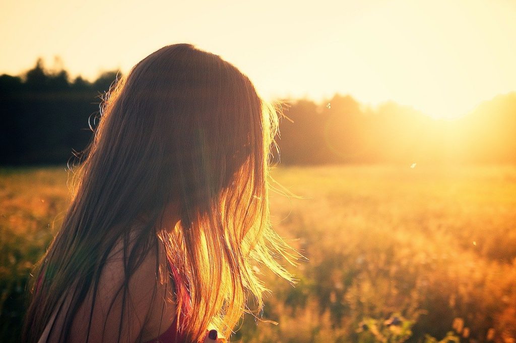 bambina con i capelli unghi di spalle che guarda il sole in un campo_Sa Mama e Su Sole
