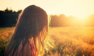 bambina con i capelli unghi di spalle che guarda il sole in un campo_Sa Mama e Su Sole