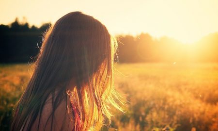 bambina con i capelli unghi di spalle che guarda il sole in un campo_Sa Mama e Su Sole