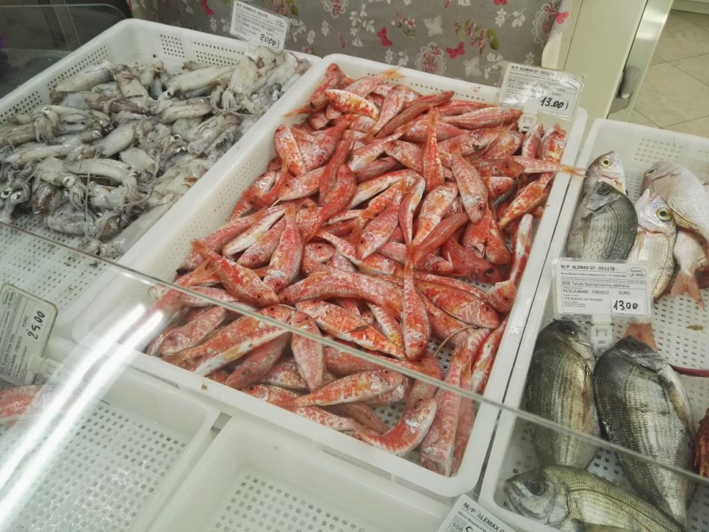 banco del pesce con cassetta di triglie in primo piano al mercato_ 