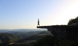 Matteo Sessini, ragazzo in verticale su una roccia panoramica sullo sfondo i monti