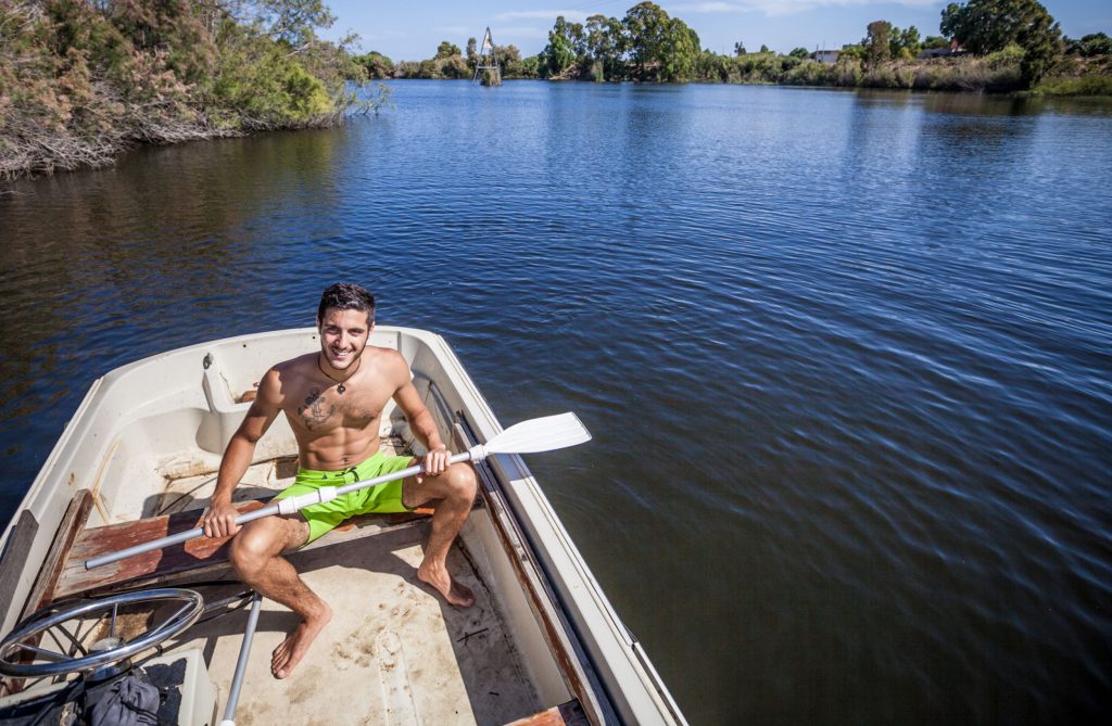 Matteo Sessini, ragazzo seduto su una canoa con un remo in mano in mezzo a un fiume