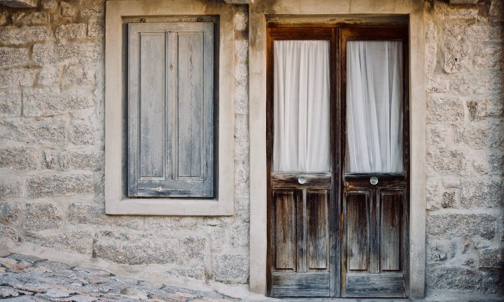 una porta e una finestra di legno in una casa antica di granito Diccius Sardi