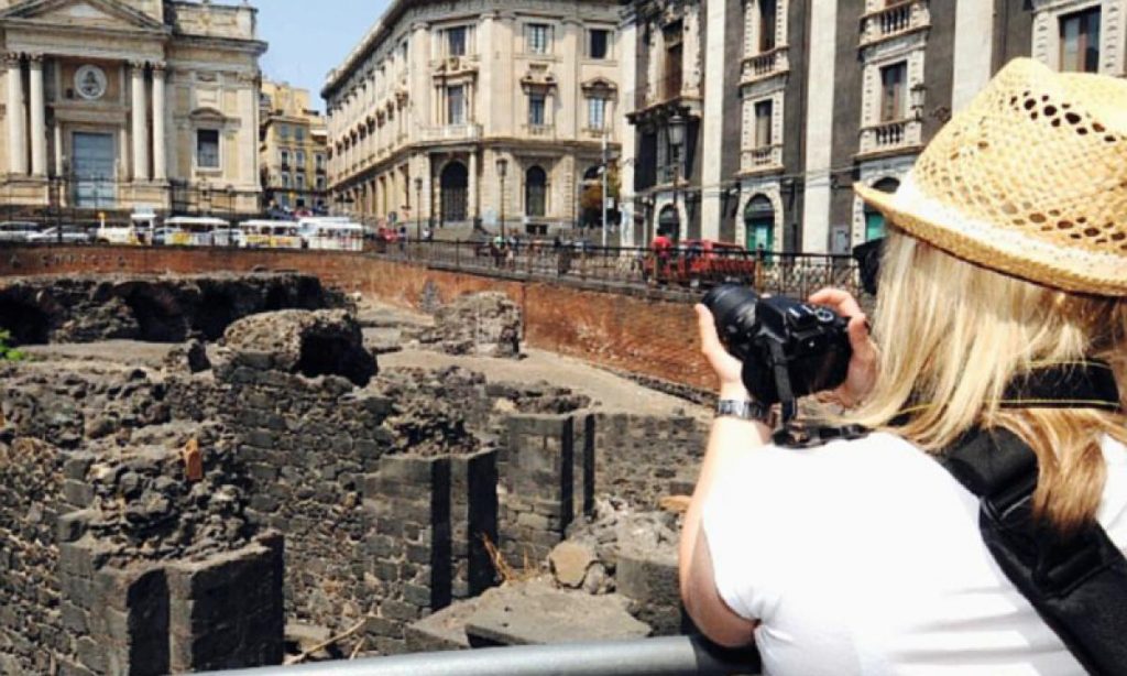 Turista di spalle che scatta una fotografia all'anfiteatro romano di Catania