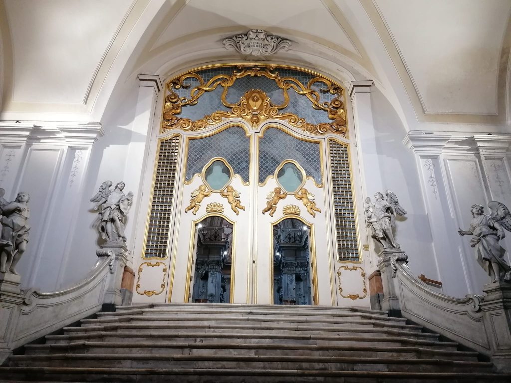Lo scalone marmoreo tardo barocco con la porta che introduce all'interno della Chiesa di San Benedetto. 