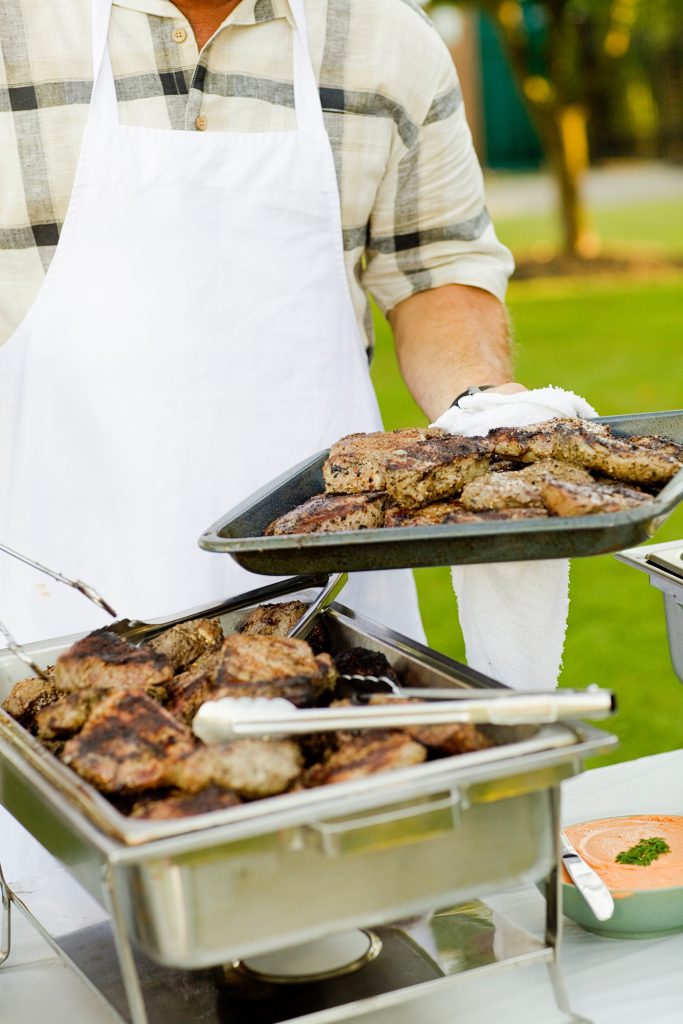 due vassoi di carne grigliata e uomo con grambiule