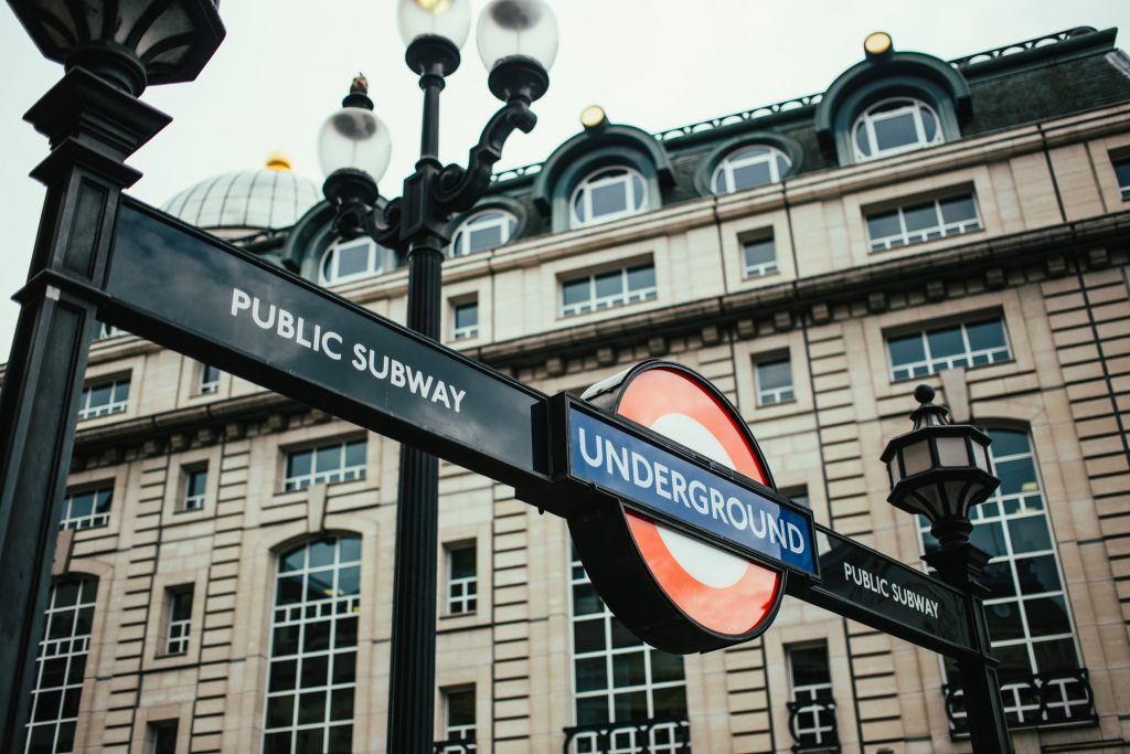 ingresso della metro segnalato dalla scritta underground su sfondo blu che taglia orizzontalmente un cerchio rosso e bianco