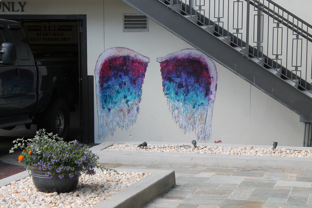 Street art - Murales rappresentativo di grandi ali sfumate in viola, azzurro e bianco