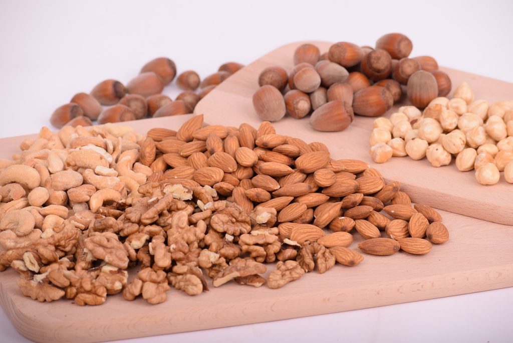 Nocciole - Tagliere di legno sopra il quale ci sono nocciole, mandorle e noci