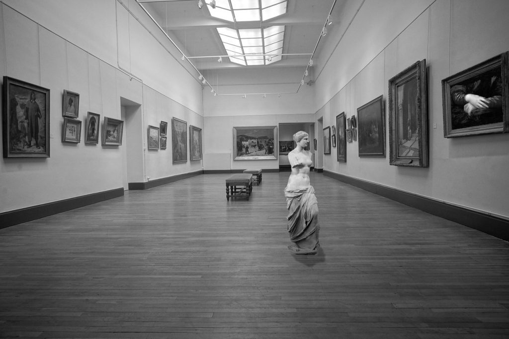 La Gioconda - foto in bianco e nero di una sala del Louvre di Parigi con quadri e statua 