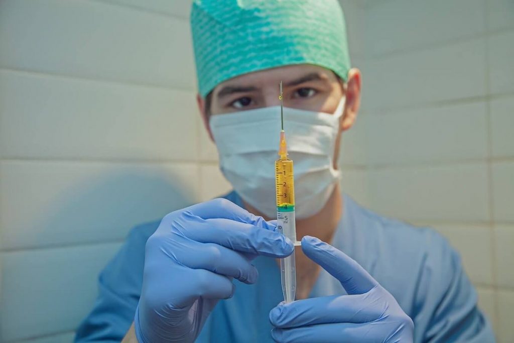 Vaccini in Francia - Dottore in camice blu con siringa