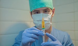 Vaccini in Francia - Dottore in camice blu con siringa